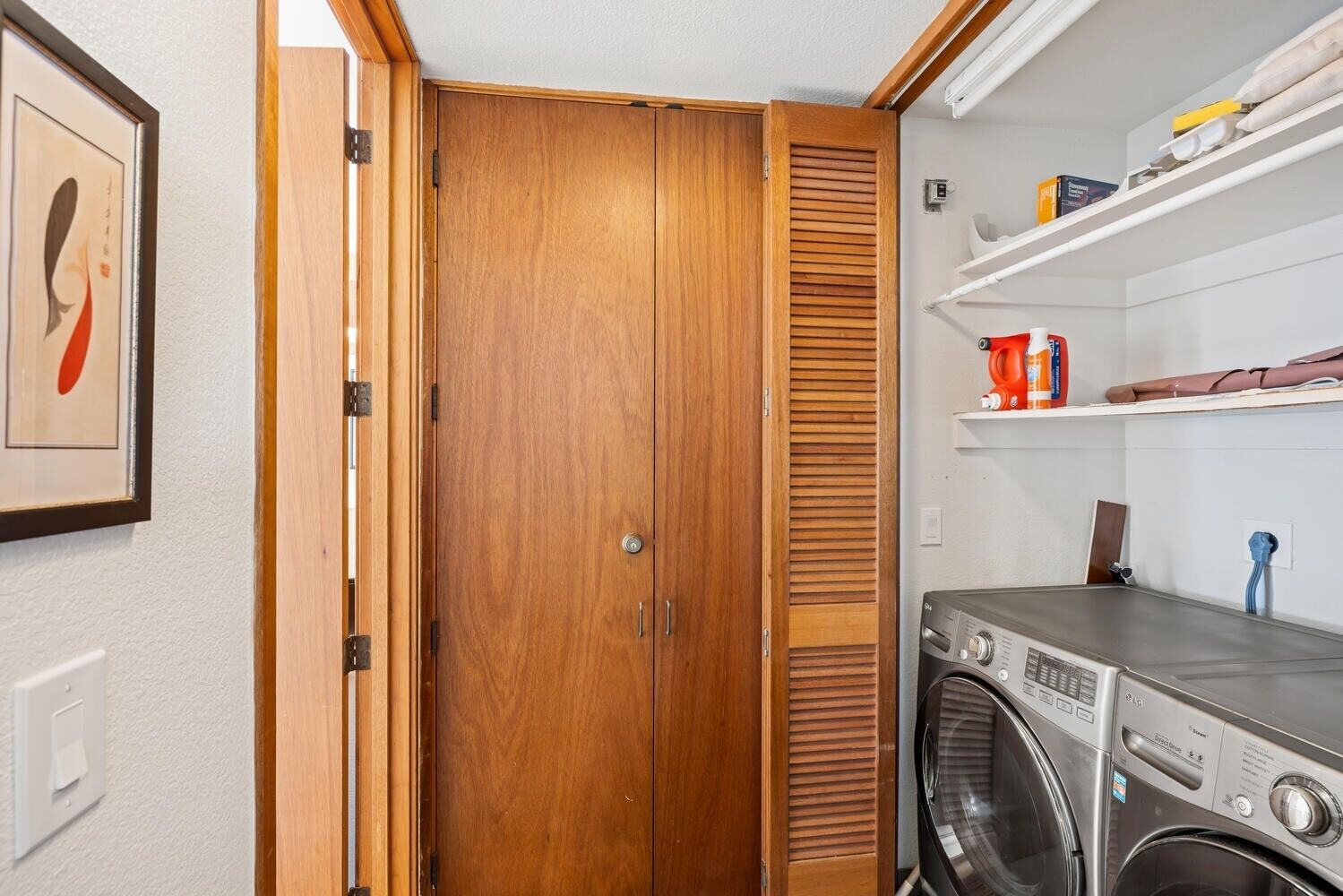 Een wasserij met een wasmachine, houten kastjes en planken met schoonmaakmiddelen.