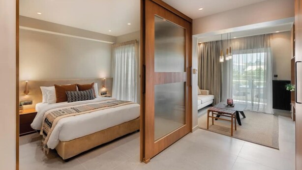 A modern hotel room with a large bed, a sliding door to a balcony, and a small seating area. - Voula Urban Escape, Bill & John Villas (Vari - Voula - Vouliagmeni)