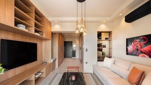 A modern living room with a flat-screen TV, wooden shelving, a marble coffee table, a sofa, and a painting of flamingos. - Voula Urban Escape, Bill & John Villas (Vari - Voula - Vouliagmeni)