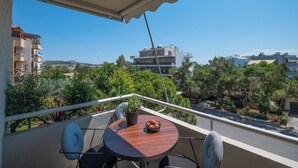 A balcony with a round table, two chairs, and a potted plant. - Voula Urban Escape, Bill & John Villas (Vari - Voula - Vouliagmeni)