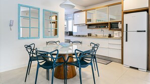 Una cocina moderna con una mesa de comedor redonda, sillas azules y un refrigerador blanco.