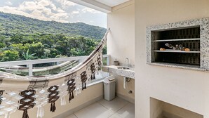 Un balcón con vistas a un paisaje verde exuberante, una hamaca, un lavamanos y un cubo de basura.