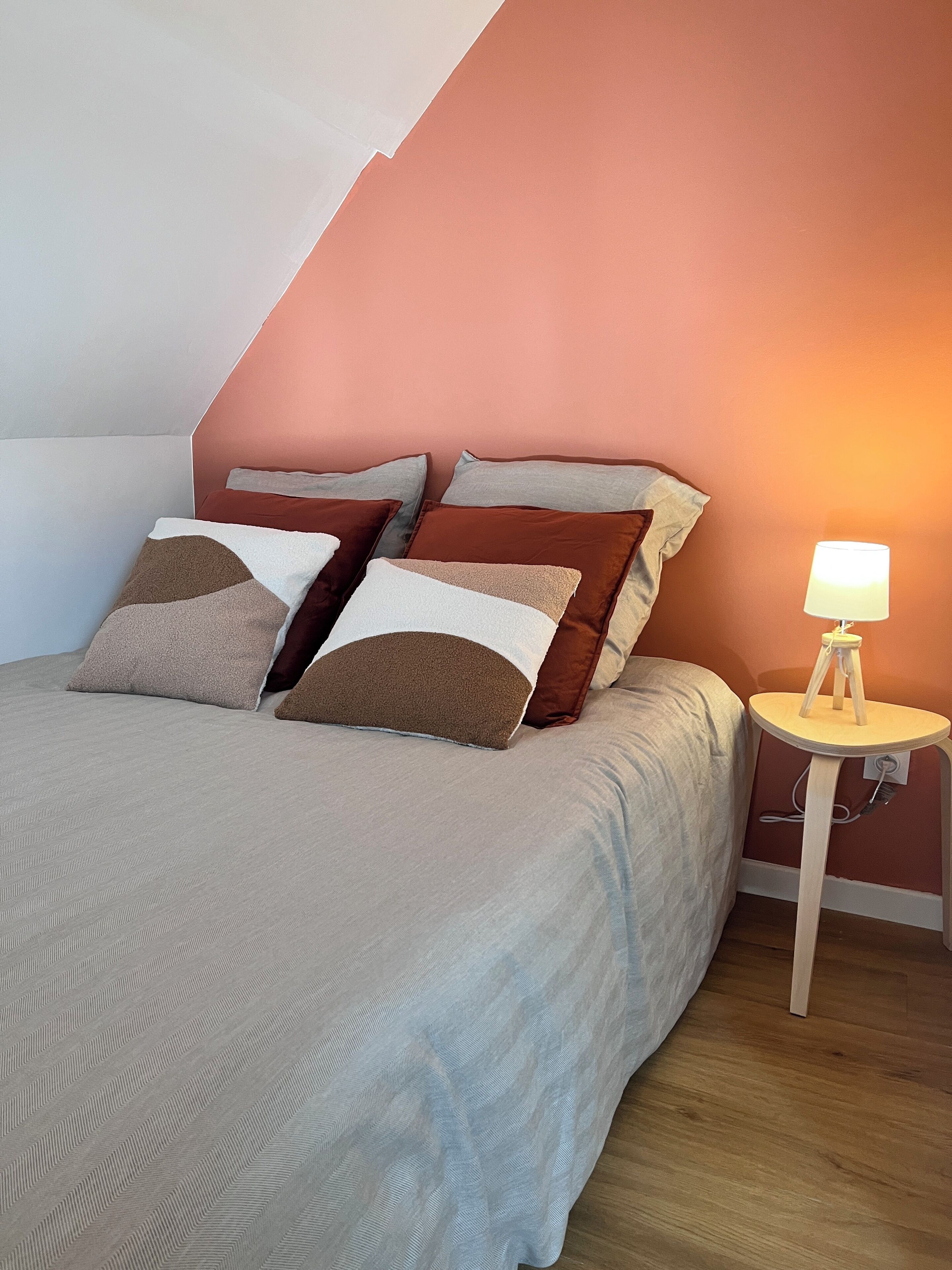 A bedroom with a bed, pillows, a nightstand, and a lamp.