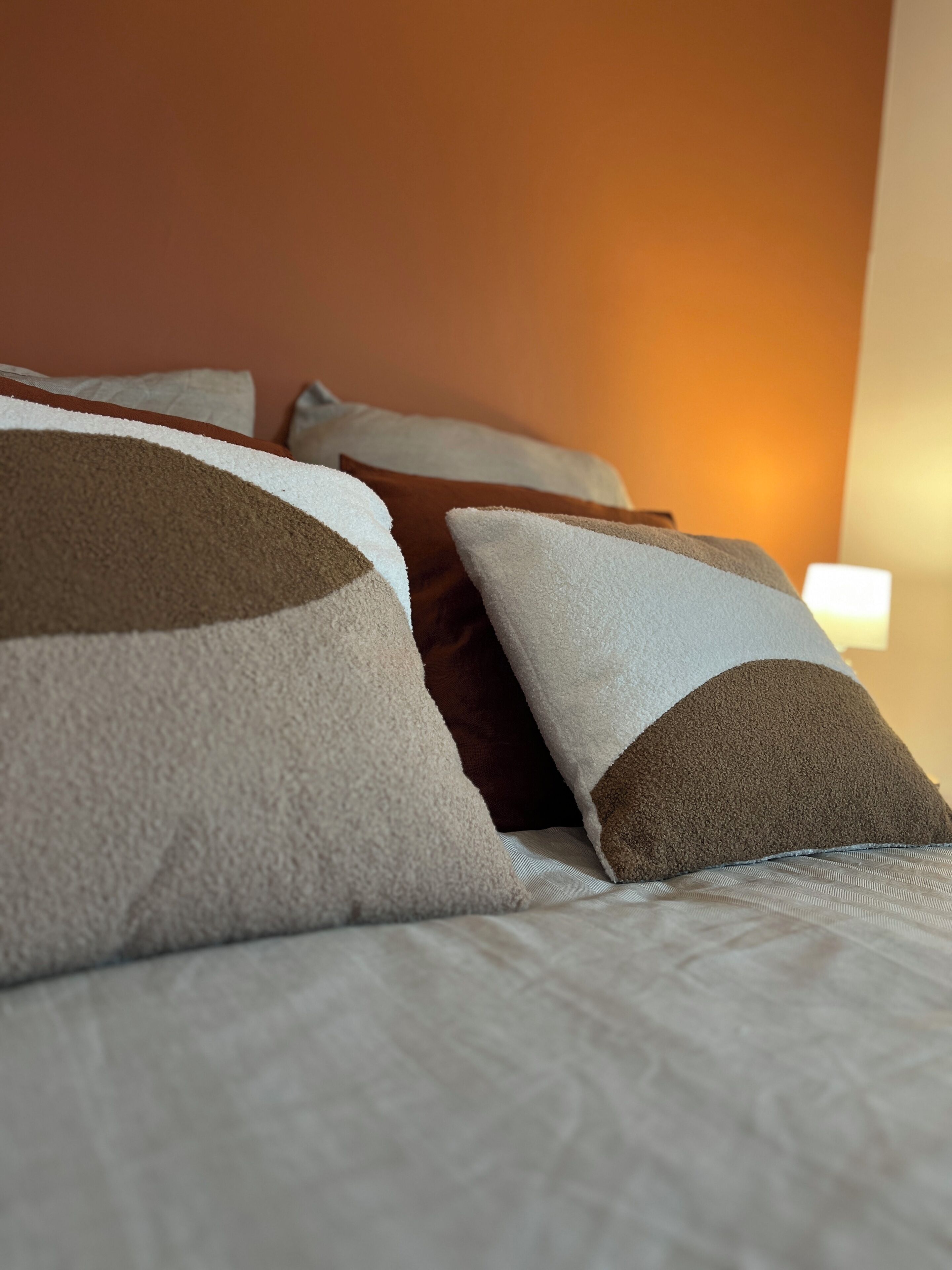 Un lit avec plusieurs oreillers, une tête de lit et une lampe de chevet.