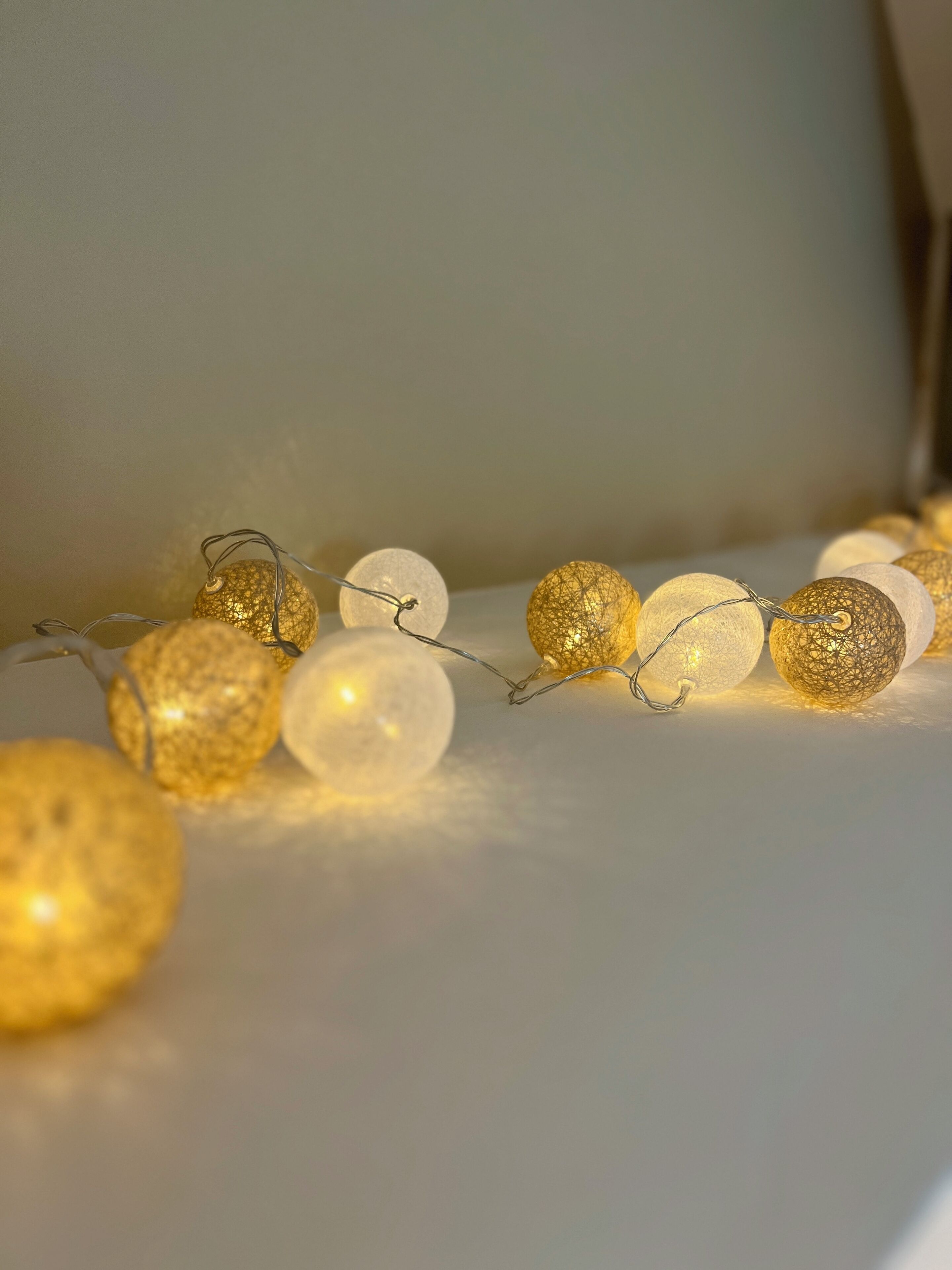 A string of decorative lights with a mix of golden and white spherical ornaments.