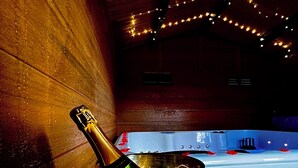 A room with a wooden wall, a bucket with a bottle, and candles.