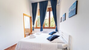 A neatly arranged bedroom with a bed, a bedside table, a radiator, and a window with curtains. - Il Cantico Home (Naples)