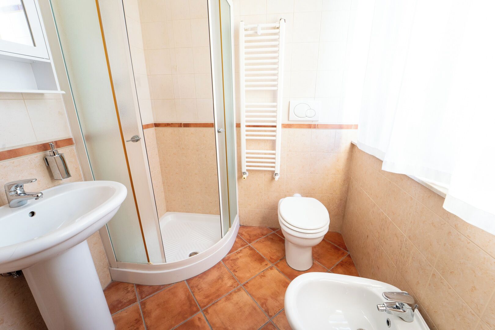 A bathroom with a shower, toilet, bidet, and sink.