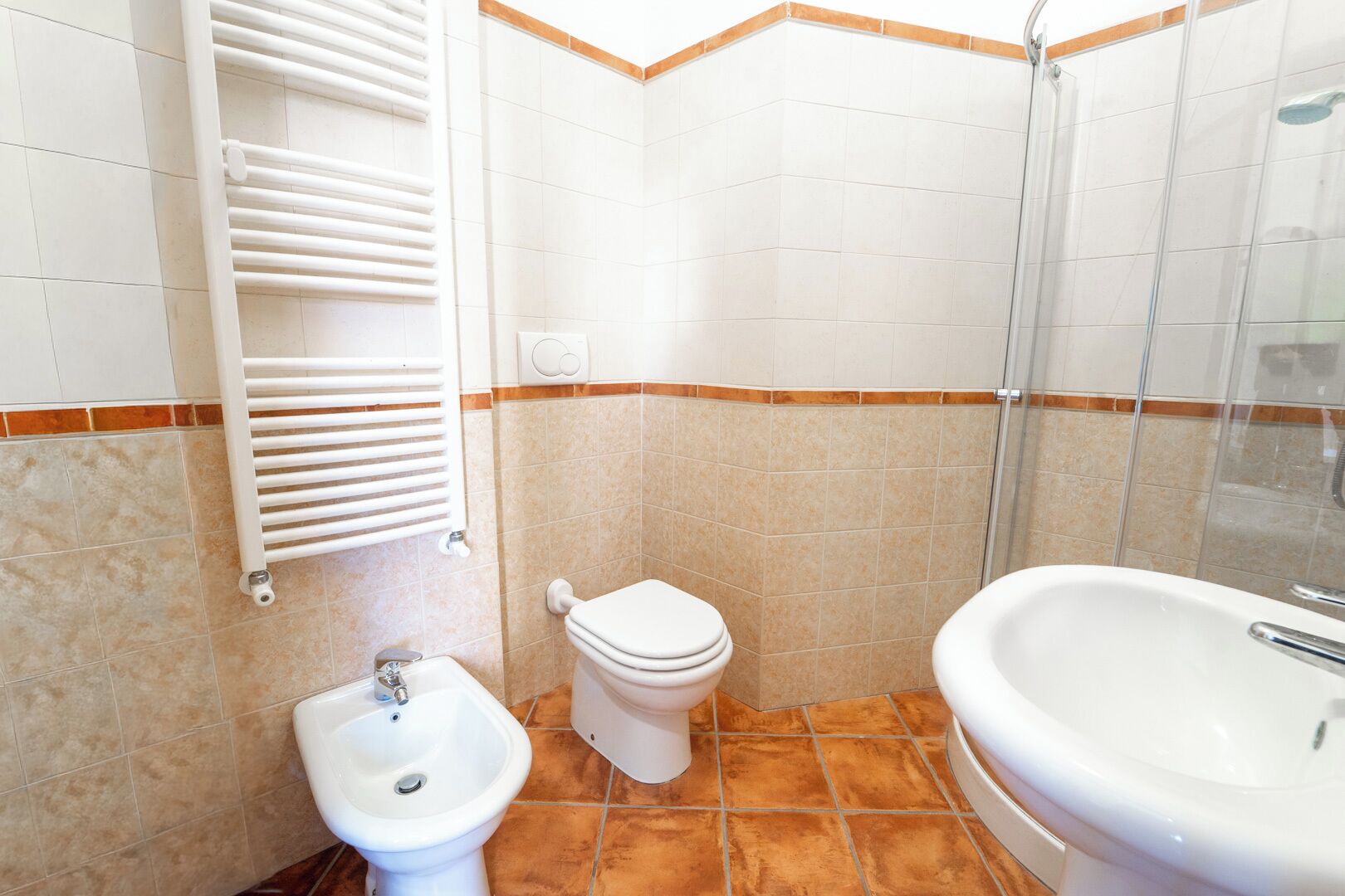 Een badkamer met toilet, bidet, wastafel en douche.