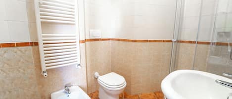 A bathroom with a toilet, bidet, sink, and shower.