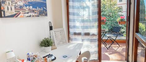 Une chambre avec balcon, une table avec des éléments pour le petit-déjeuner, une petite plante et un panneau d’accueil.