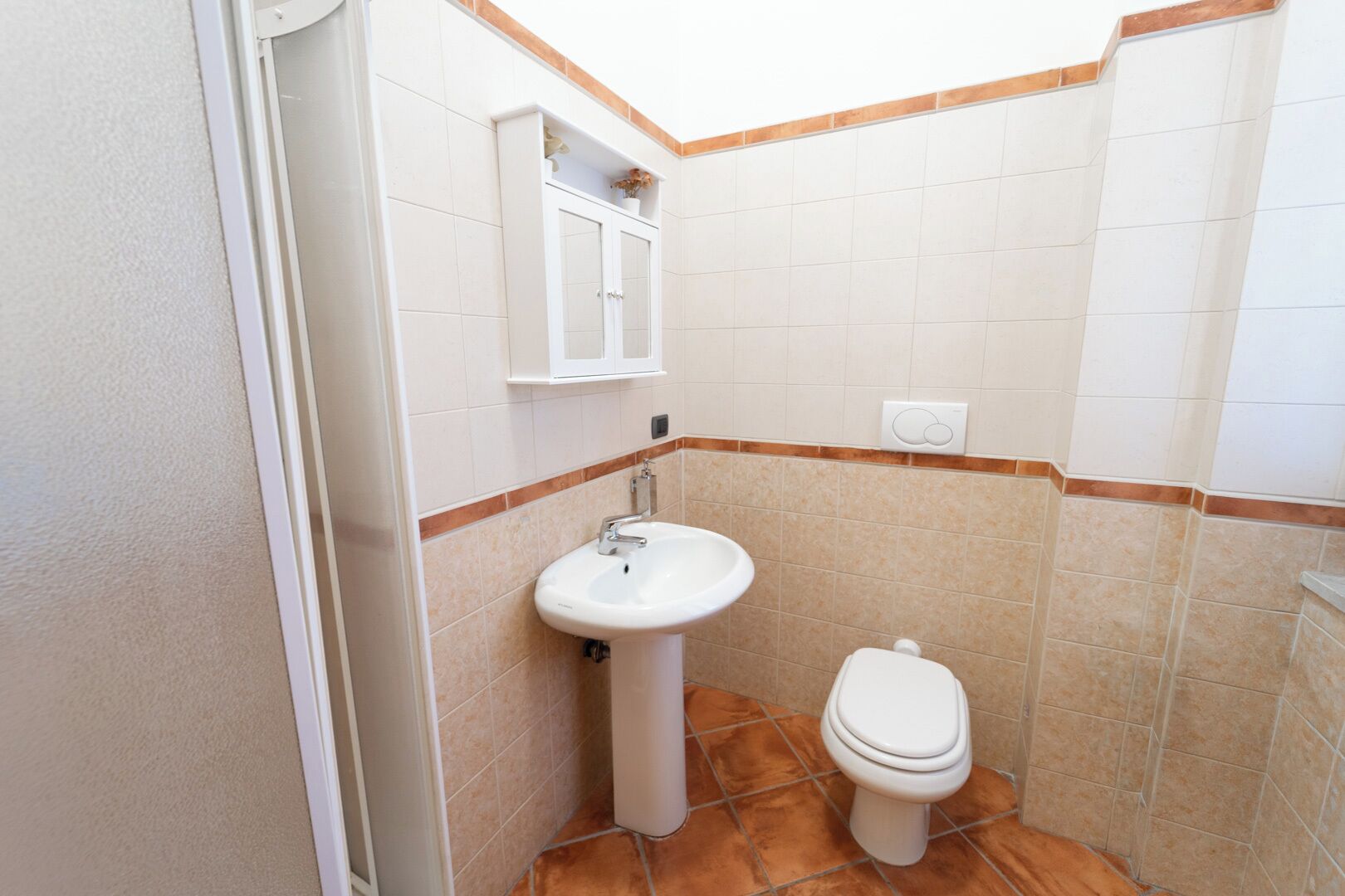 A small bathroom with a white sink, a toilet, and a cabinet above the sink.
