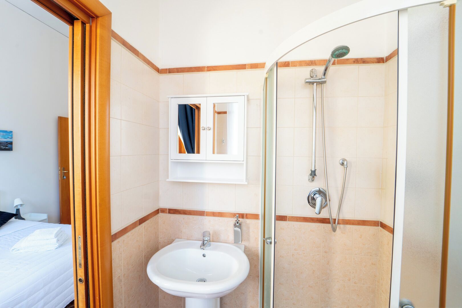 Une salle de bain d’hôtel équipée d’une douche, d’un lavabo et d’un meuble avec miroir.