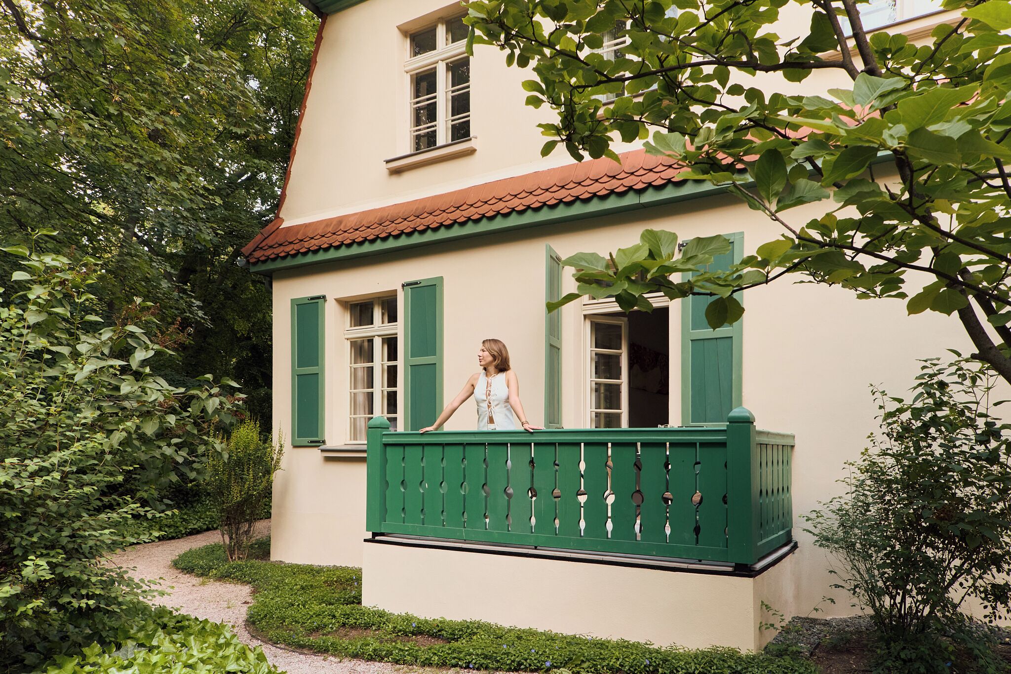 Een huis met twee verdiepingen en een balkon, omringd door groen.