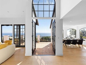 Un vaste espace de vie avec une grande porte vitrée donnant sur une terrasse offrant une vue sur la mer.