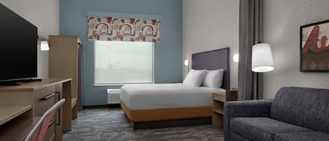 Una habitación de hotel con cama, escritorio, silla y sofá.