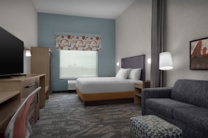 Una habitación de hotel con cama, escritorio, silla y sofá.