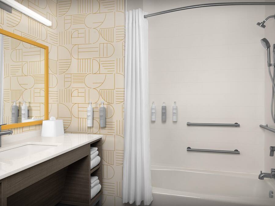 A modern bathroom with a shower, a sink with a mirror, and toiletries.