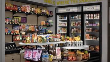 Una tienda de comestibles con estantes llenos de refrigerios, una sección con neveras y una exhibición de agua embotellada y bocadillos.