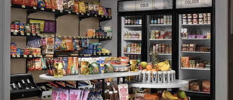Ein Supermarkt mit Regalen voller Snacks, einer Kühltheke und einer Auslage mit Wasserflaschen und Snacks.