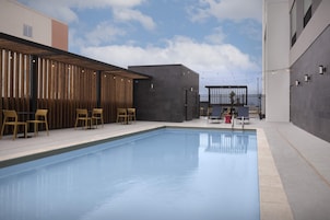 Una piscina con sillas y mesas, rodeada de edificios de diseño moderno.