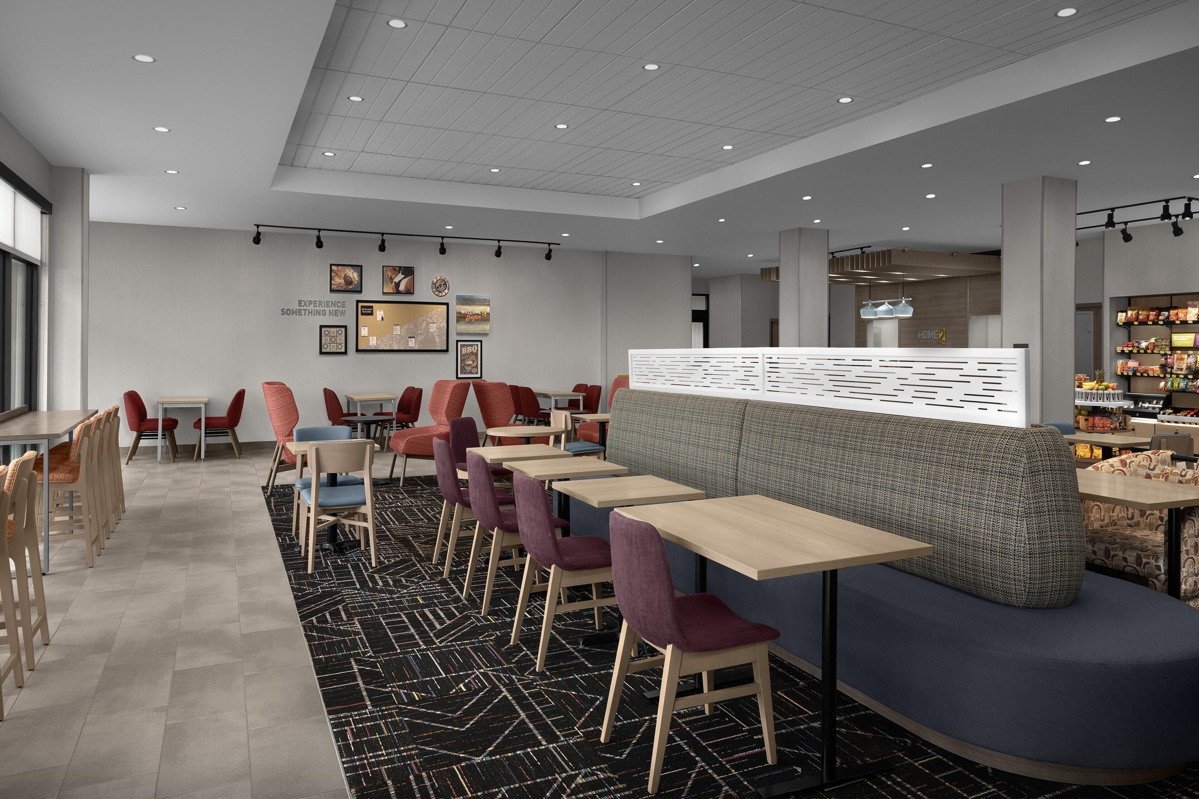 Ein modernes Restaurant mit einer langen Theke, verschiedenen Sitzmöglichkeiten wie Boxsitzgelegenheiten und Stühlen, und einem gemusterten Teppich.