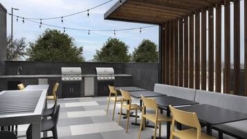 An outdoor patio with a barbecue grill, seating area, and string lights.
