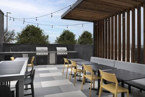 An outdoor patio with a barbecue grill, seating area, and string lights. - Home2 Suites By Hilton Taylor (Taylor)