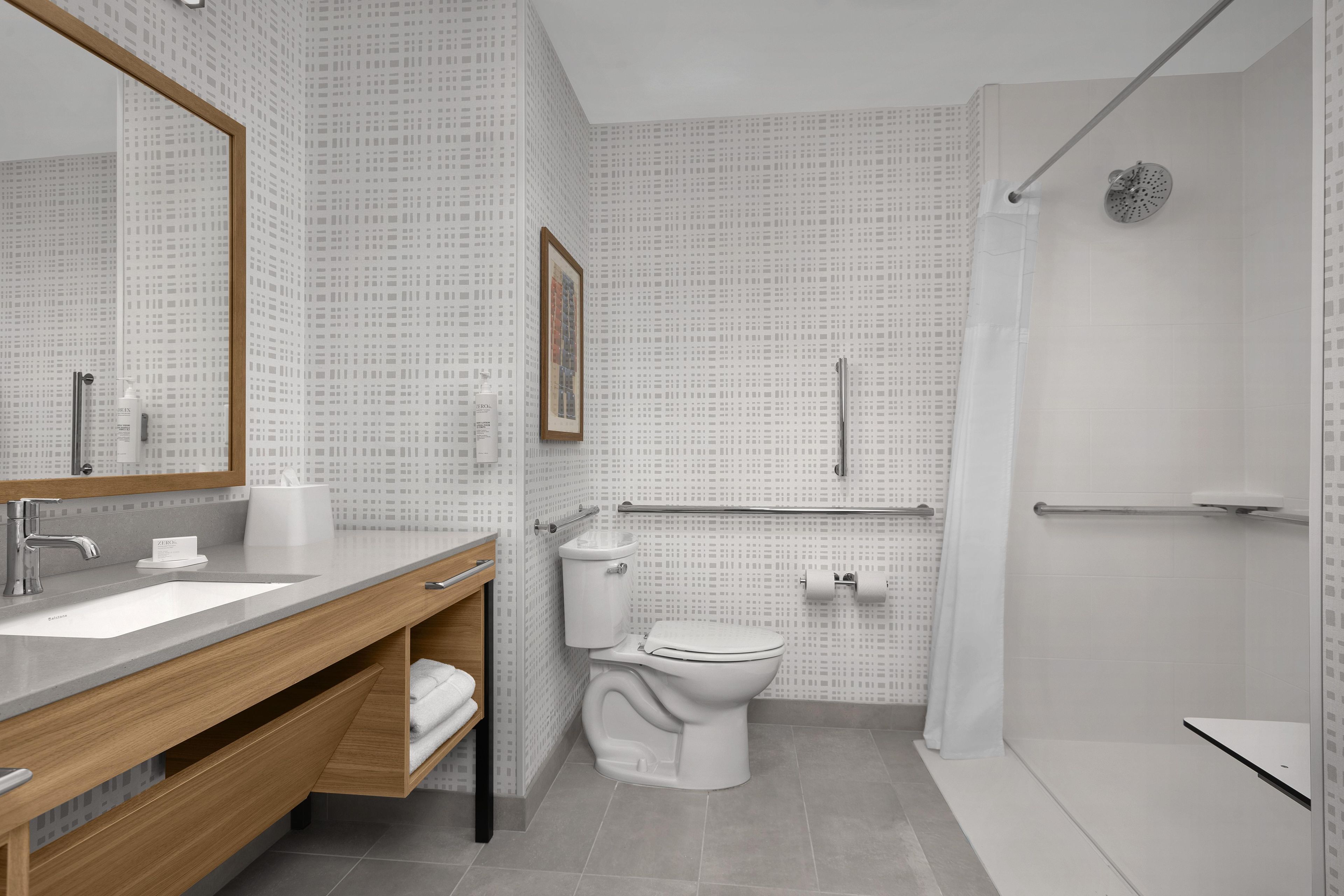 A modern bathroom with a large mirror, a sink, a toilet, and a shower.