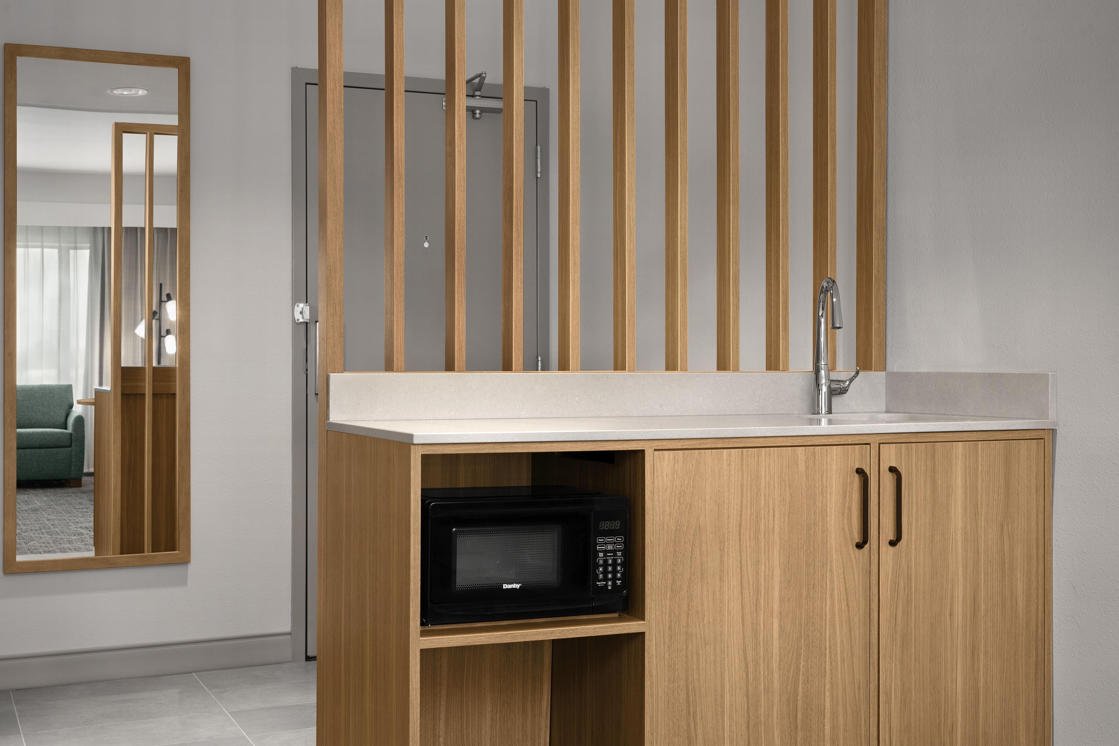 A modern kitchen with a wooden cabinet, a microwave, and a sink.