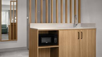 A modern kitchen with a wooden cabinet, a microwave, and a sink.