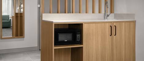 A modern kitchen with a wooden cabinet, a microwave, and a sink.