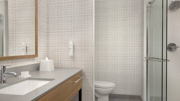 A modern bathroom with a large mirror, a sink, and a toilet.