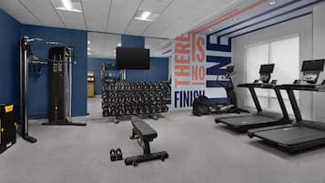 A gym with exercise equipment, treadmills, and dumbbells.