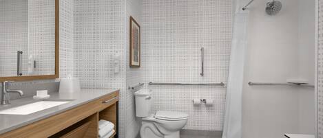 A modern bathroom with a large mirror, a sink, a toilet, and a shower.