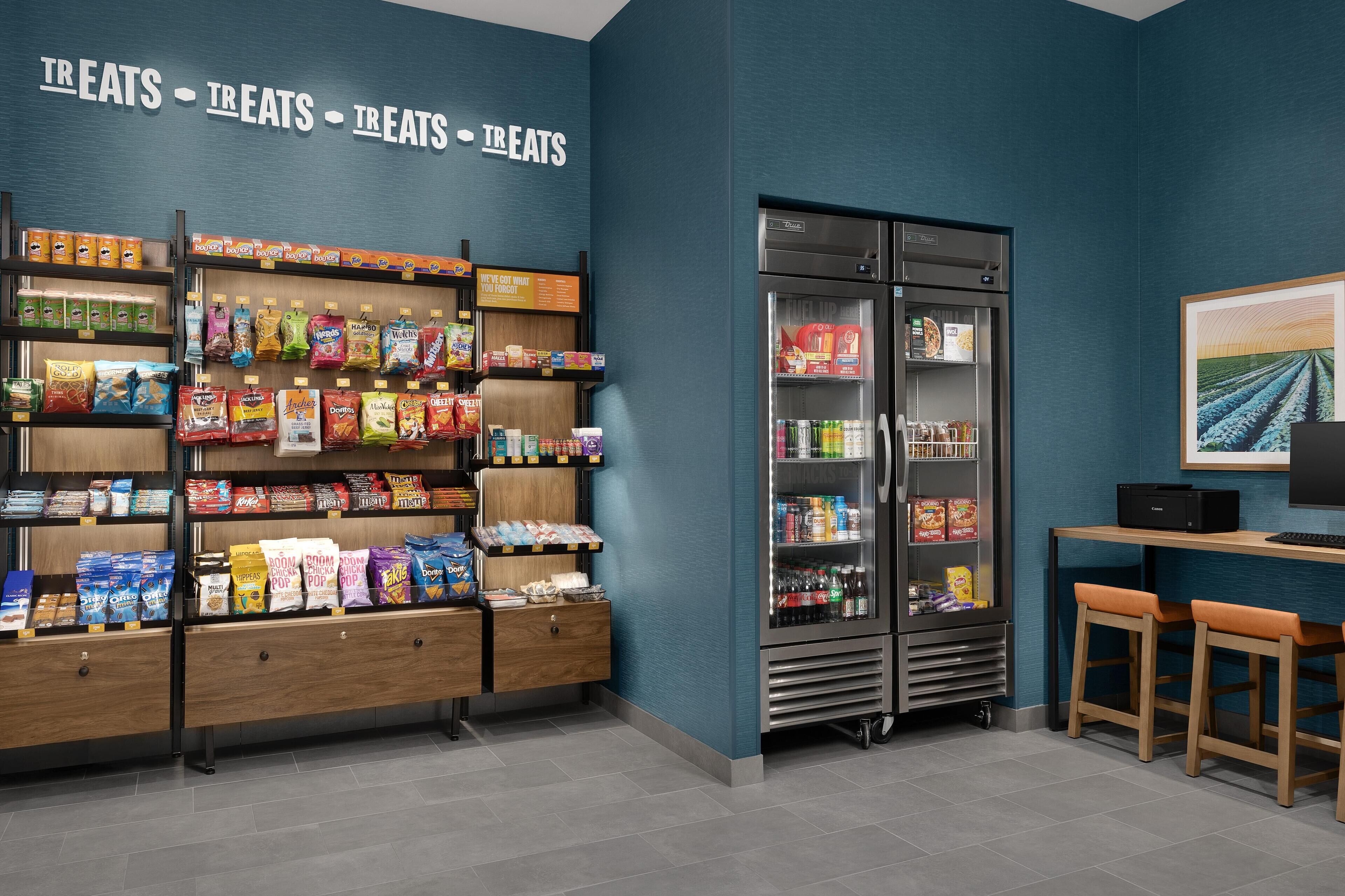 A snack display area with shelves of various packaged snacks and a refrigerated section with beverages.