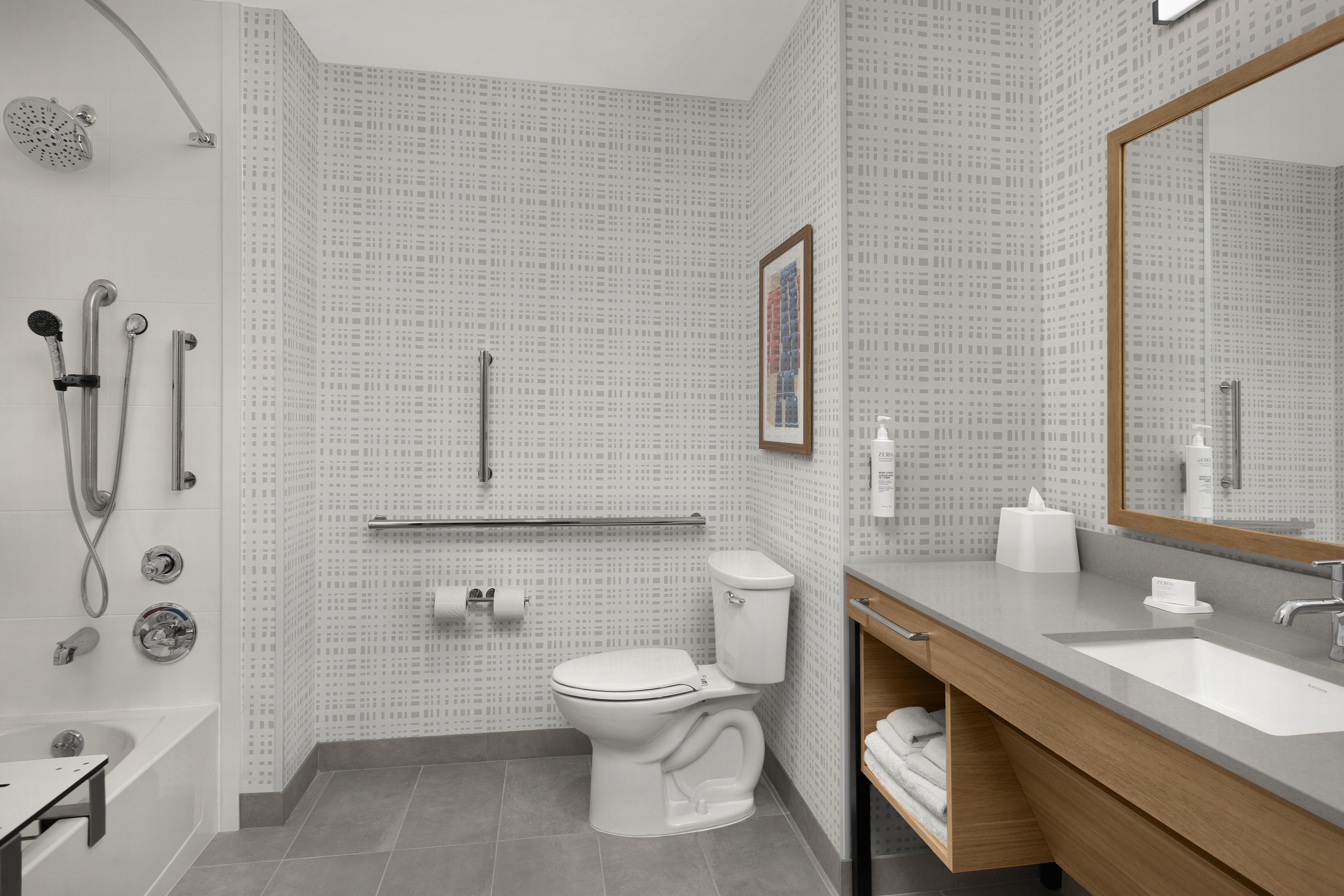 Un baño moderno con bañera, ducha, inodoro y tocador con lavabo.