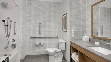 Un baño moderno con bañera, ducha, inodoro y tocador con lavabo.