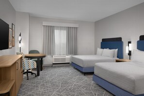 Habitació d'hotel amb un llit, escriptori, cadira, finestra amb cortines i aire condicionat fixat a la paret.