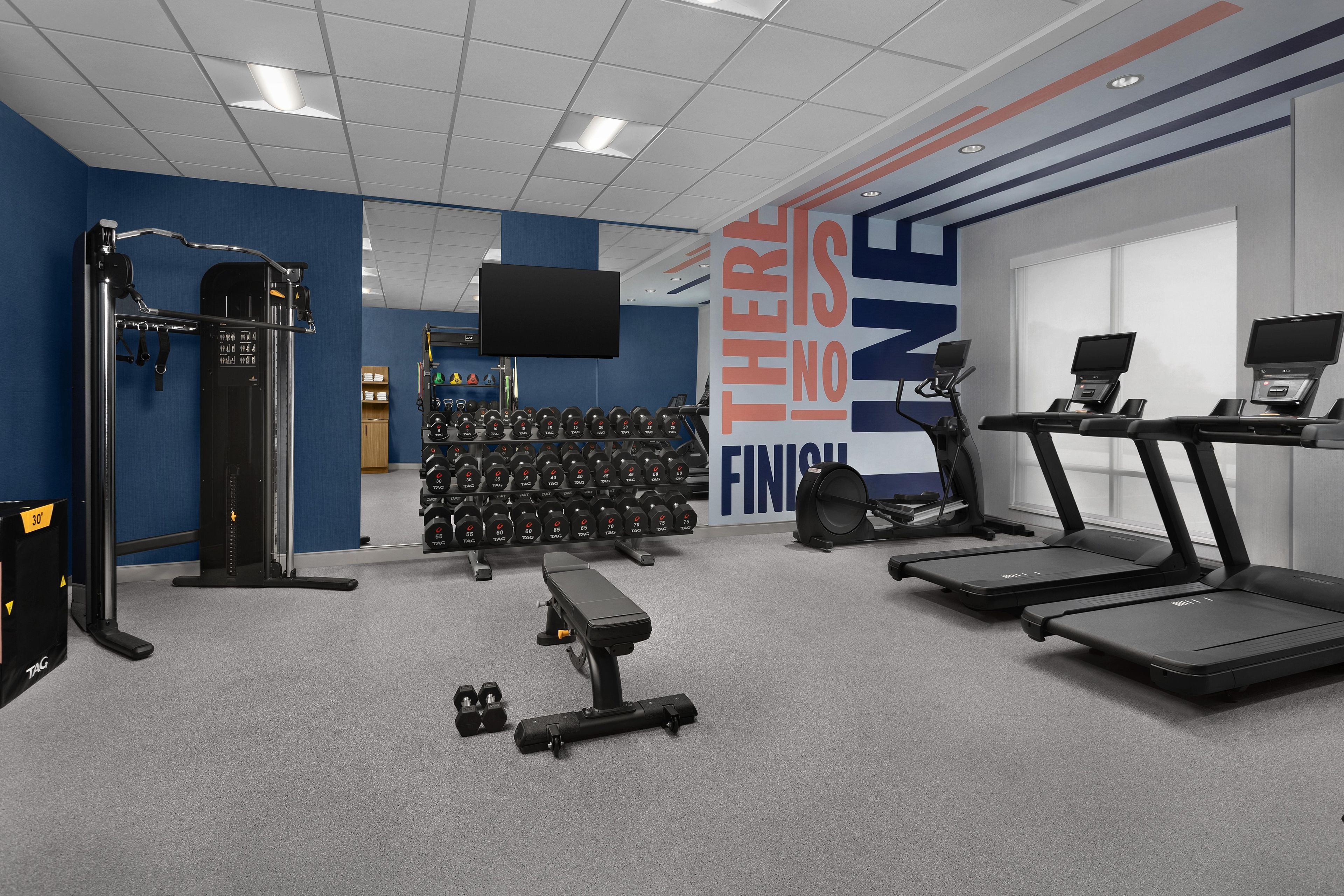 A gym with exercise equipment, treadmills, and a motivational wall.