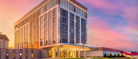 A modern hotel with a prominent entrance, multiple floors, and a well-lit facade.