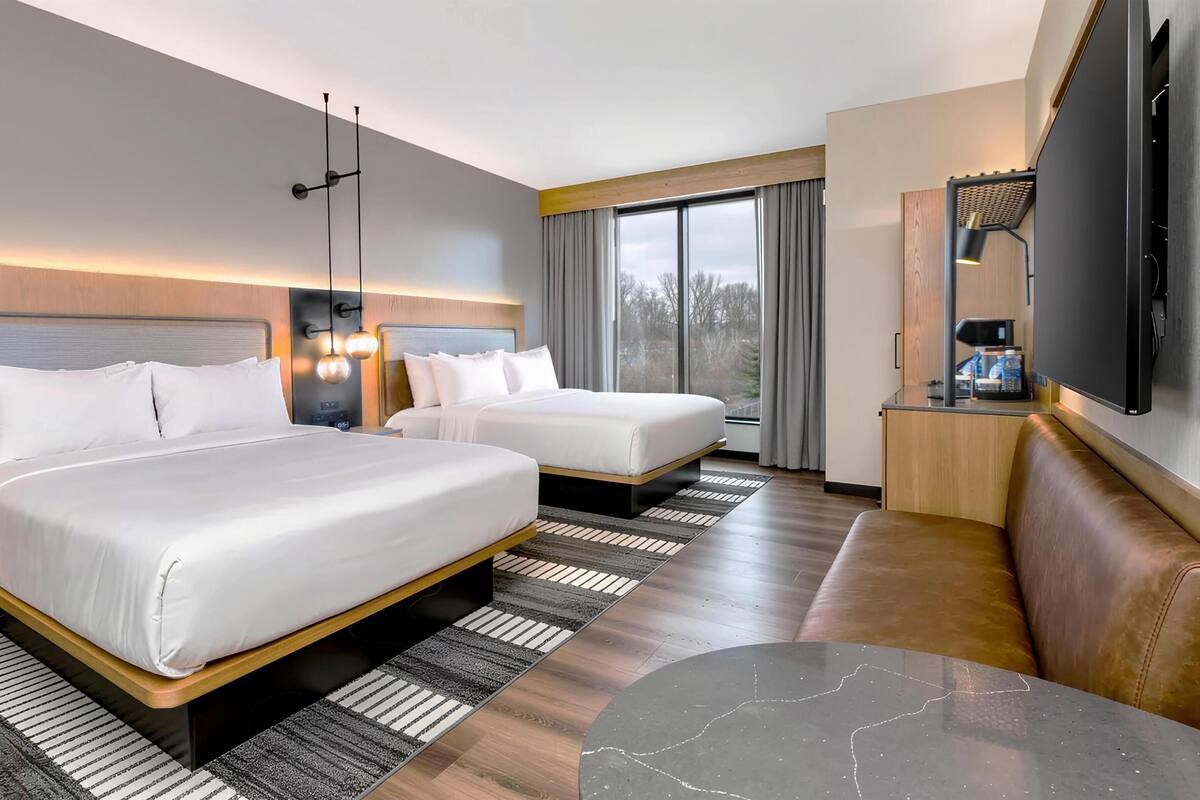 Une chambre d’hôtel avec deux lits, un canapé, une télévision et une machine à café.