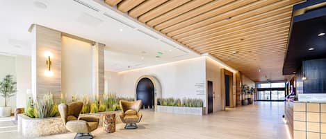 Eine moderne Hotelhalle mit Holzbalkendecke, einer Rezeption und Sitzbereichen.