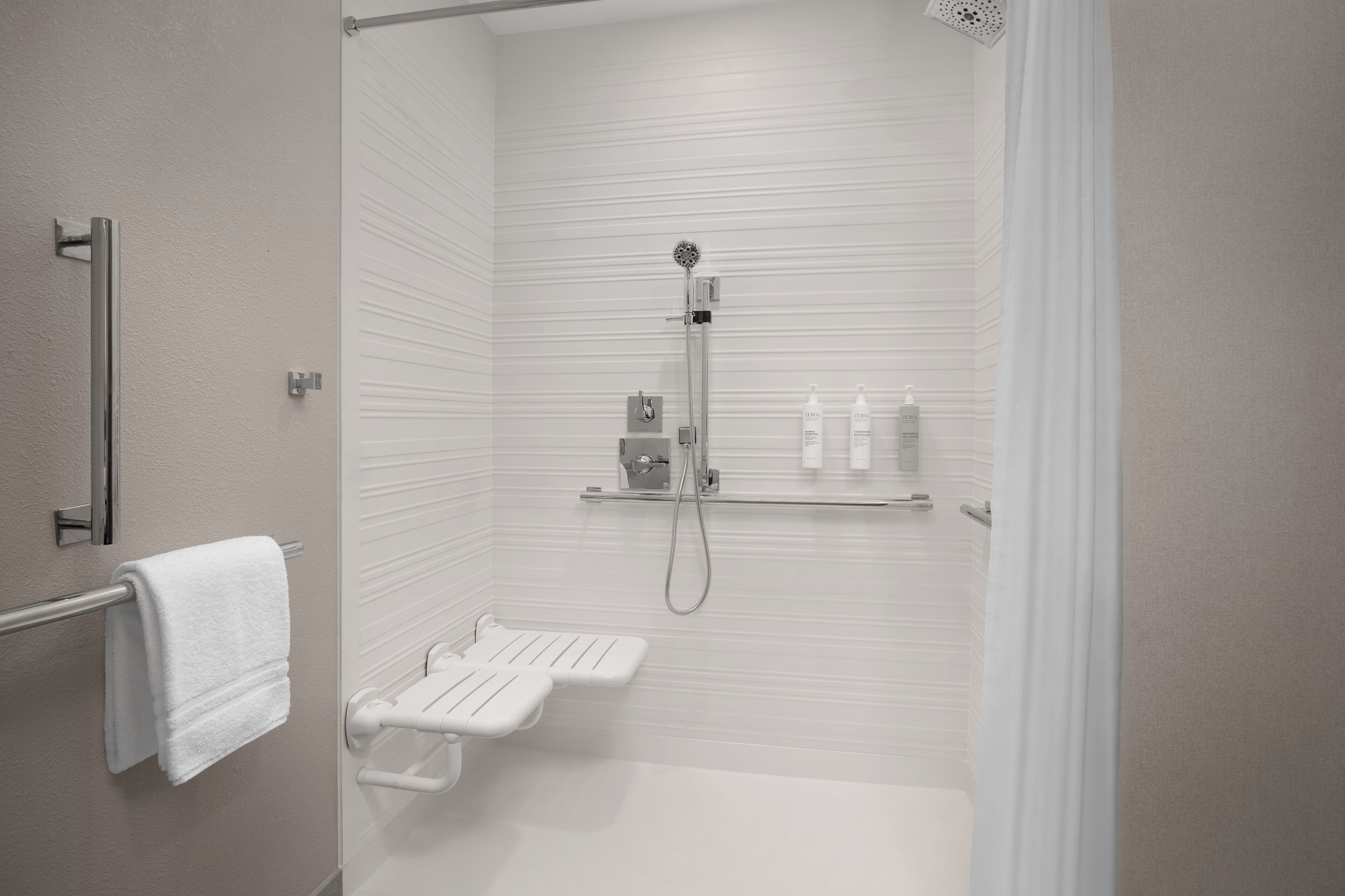 A modern bathroom with a walk-in shower, a towel rack, and a shelf with toiletries.