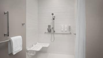 A modern bathroom with a walk-in shower, a towel rack, and a shelf with toiletries.