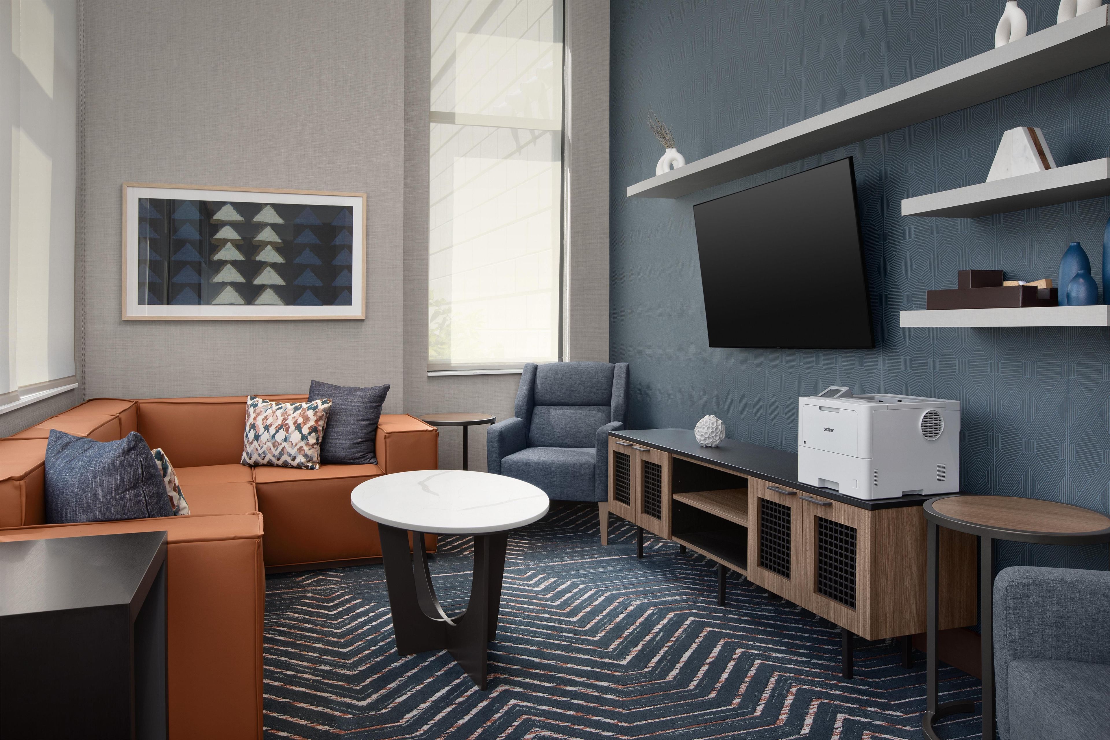 A modern living room with a sofa, armchairs, a coffee table, a TV, and a printer.