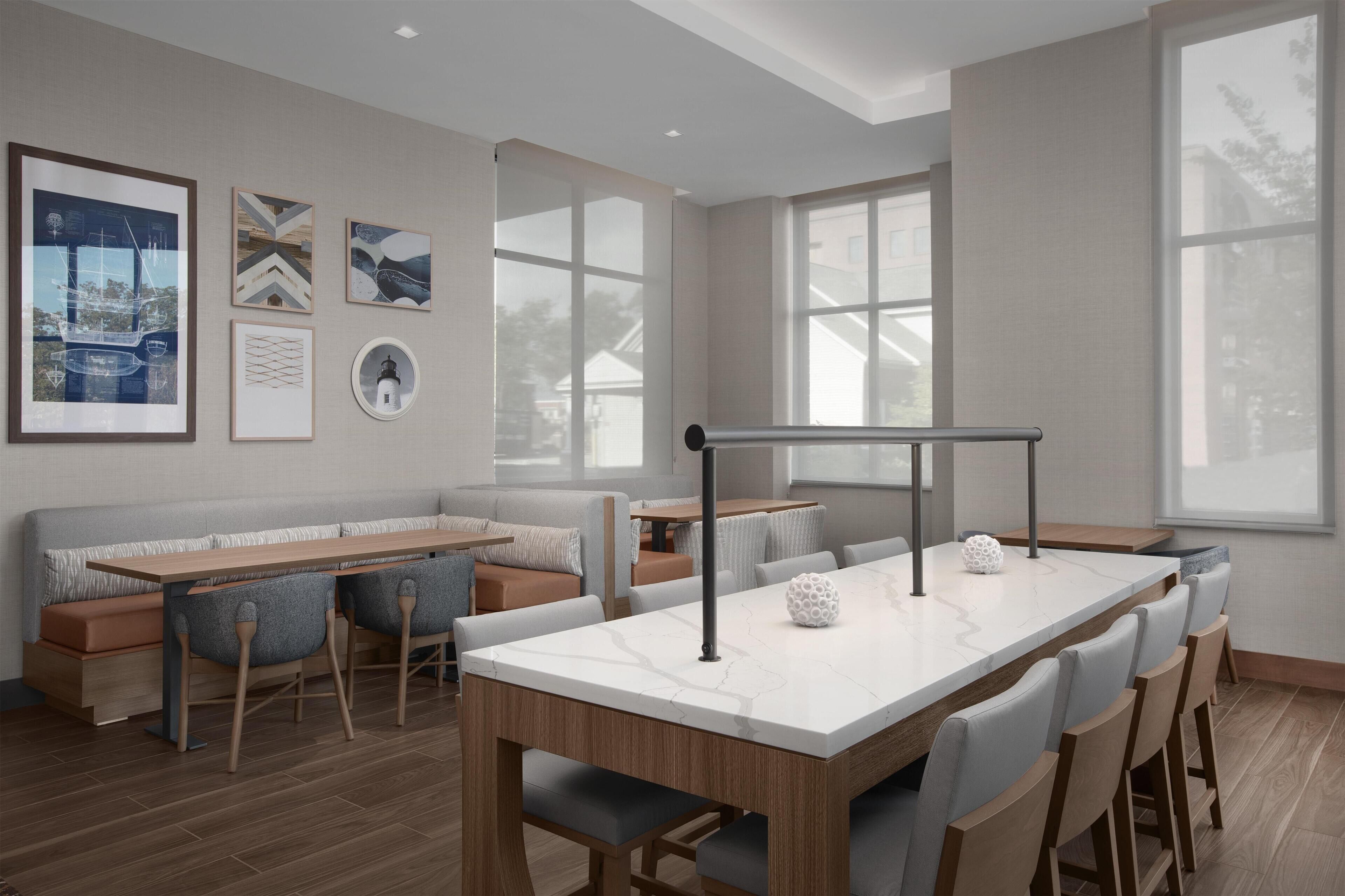 A modern dining area with a long table, cushioned seating, and artwork on the walls.