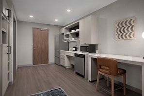 A modern kitchen with built-in appliances, a wooden door, and a white countertop.