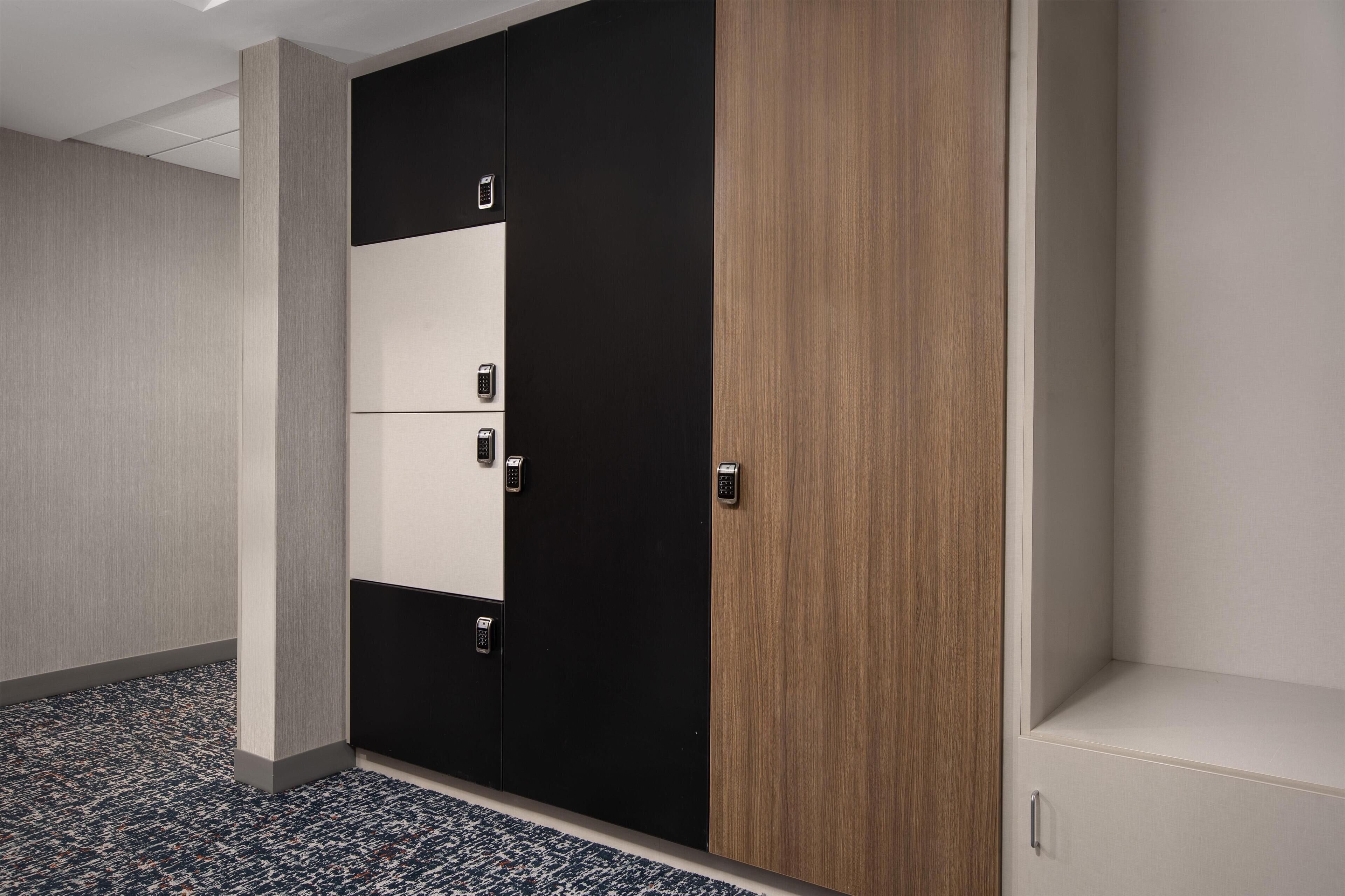 A hotel room with a wardrobe, a carpeted floor, and a plain wall.