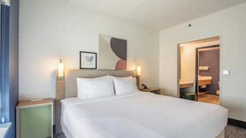 Una habitación de hotel con cama, mesitas de noche, teléfono en la pared y puerta de baño.